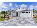 Beautiful home showcasing a spacious three car garage with a uniquely patterned driveway at 4874 Noreen Ct, The Villages, FL 32163
