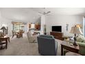 Open-concept living room with neutral carpet, ceiling fan and seamlessly connected to dining and kitchen areas at 516 Junction Pl, The Villages, FL 32163