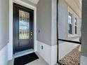 Close-up of the front door featuring decorative glass, black hardware, and neutral exterior paint at 655 Conservation Blvd, Groveland, FL 34736