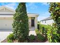 View of the covered front porch, enhanced by lush landscaping, next to the two-car garage at 8128 Penrose Pl, Wildwood, FL 34785