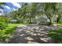 Long paved driveway leads to the home with mature trees providing shade and lush green lawns surrounding at 9223 Silver Lake Dr, Leesburg, FL 34788
