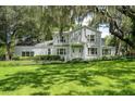 Charming two-story home with mature landscaping, lush green lawn, and beautiful Spanish moss-covered trees at 9223 Silver Lake Dr, Leesburg, FL 34788
