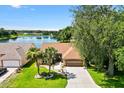 Picturesque aerial view of a home with a lake view, mature trees, and well-maintained green lawns at 1032 Ventura Dr, Lady Lake, FL 32159