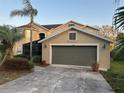 Exterior view of home and garage showing a well manicured lawn, paved driveway and mature palm trees at 1096 Linkside Ct, Apopka, FL 32712