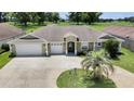 Beautiful home with a three-car garage, mature landscaping, and a circular driveway leading to a covered entrance at 12407 Ne 48Th Loop, Oxford, FL 34484