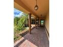 Covered front porch with brick pavers, decorative columns, and hanging lights at 17329 Se 115Th Ter, Summerfield, FL 34491