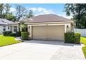 Attractive home featuring a well-kept lawn, manicured shrubs, and a convenient two-car garage with a neutral-toned door at 2389 Grand Poplar St, Ocoee, FL 34761