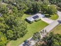 Aerial view of a single-story home with solar panels, well-maintained landscaping, and a metal roof at 2450 W Lake Dr, Deland, FL 32724