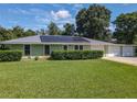 Charming single-story home with a well-manicured lawn, metal roof and three car garage at 2450 W Lake Dr, Deland, FL 32724