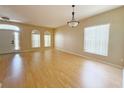 Spacious living room with light-colored hardwood floors, large windows, and a decorative light fixture at 3416 Capland Ave, Clermont, FL 34711