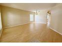 Bright living room with hardwood floors, neutral walls, a modern light fixture and view into kitchen area at 3416 Capland Ave, Clermont, FL 34711