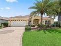 Well-maintained home featuring a lush front yard, palm trees, and a decorative circular driveway at 591 Allenwood Loop, The Villages, FL 32162
