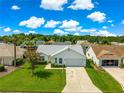 Elevated view of a well-manicured front lawn leading up to a white single-story house in a verdant neighborhood at 804 Santa Rita Way, Lady Lake, FL 32159