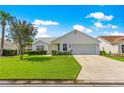 Inviting single-story home featuring a well-kept lawn, a two-car garage, and trimmed hedges under a clear sky at 804 Santa Rita Way, Lady Lake, FL 32159
