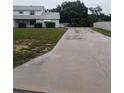 Long concrete driveway leading to a home with large yard and covered parking at 11532 Beaman Cir, Clermont, FL 34711
