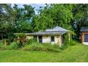 Exterior of the property featuring a quaint yellow house and overgrown landscaping at 16615 Oklahoma St, Clermont, FL 34715