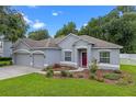 Well-manicured lawn with flower beds highlighting this single-story house with a three-car garage at 1702 Hoofprint Ct, Fruitland Park, FL 34731