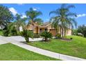 Beautifully landscaped home with an expansive driveway, lush lawn and mature palm trees at 1892 Sanderling Dr, Clermont, FL 34711
