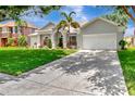 View of the home's driveway and exterior, showcasing its well-maintained lawn and lush landscaping at 233 Largovista Dr, Oakland, FL 34787