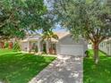 Lovely one-story home with a well-kept lawn, mature trees, and a long driveway leading to a two-car garage at 233 Largovista Dr, Oakland, FL 34787