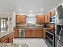 Well-lit kitchen featuring stainless steel appliances, granite countertops, wooden cabinetry, and modern tile flooring at 2620 Persimmon Loop, The Villages, FL 32162