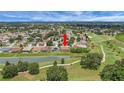 Aerial view of a home situated on a beautiful landscaped lot with a lake view in a golf community at 2880 Manor Downs, The Villages, FL 32162