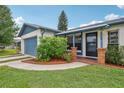 Inviting front entrance featuring a brick-lined walkway, blue accents, and well-maintained landscaping at 550 Floral Dr, Kissimmee, FL 34743