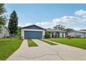 Well-maintained single-story home showcasing a concrete driveway, blue garage door, and lush green lawn at 550 Floral Dr, Kissimmee, FL 34743