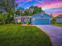 Charming single-story home with a well-manicured lawn, blue siding, and an attached two-car garage at 627 Timbercrest Dr, Leesburg, FL 34748
