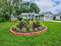 Landscaped front yard featuring a circular flower bed with vibrant plants and lush green grass at 627 Timbercrest Dr, Leesburg, FL 34748