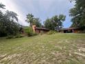Single-story home featuring an open carport, lush landscaping, and a spacious yard at 6616 Tuscawilla Dr, Leesburg, FL 34748