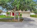 Charming single-story home featuring a red front door, red shutters, well-manicured landscaping, and a spacious two-car garage at 1216 Cheshire St, Groveland, FL 34736