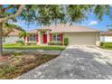 Charming single-story home featuring a red front door, red shutters, and well-manicured landscaping at 1216 Cheshire St, Groveland, FL 34736