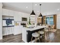 Modern kitchen features white cabinetry, a kitchen island with pendant lights, and an adjacent dining area at 13108 Serene Glade Rd, Winter Garden, FL 34787