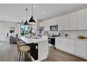 Open-concept kitchen featuring white cabinets, stainless steel appliances, a kitchen island, and bar stool seating at 13108 Serene Glade Rd, Winter Garden, FL 34787