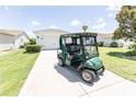 Driveway scene of a golf cart at a charming home with a manicured lawn and beautiful landscaping at 1654 Blossom Ter, The Villages, FL 32162
