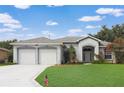 Charming single-story home with a well-manicured lawn, double garage, and beautiful landscaping at 22125 Draw Bridge Dr, Leesburg, FL 34748