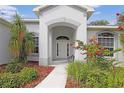 Inviting covered front porch with elegant archway, decorative plants, and cozy bench seating at 22125 Draw Bridge Dr, Leesburg, FL 34748