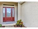 Up close view of a beautiful red front door framed with glass and sidelights at 26653 Otter Creek Ln, Leesburg, FL 34748