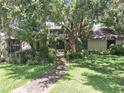 Charming home exterior with lush landscaping, mature trees, and a welcoming walkway to the front door at 29205 Old E Ml, Tavares, FL 32778