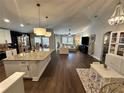 Open-concept living room and kitchen space with hardwood floors and modern lighting fixtures at 295 Whirlaway Drive, Davenport, FL 33837