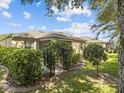 A home's backyard with well maintained greenery, trimmed bushes and trees, and pavers at 3677 Serena Ln, Clermont, FL 34711