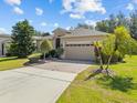 Charming single-story home with a well-manicured lawn, mature landscaping, and a brick driveway at 3677 Serena Ln, Clermont, FL 34711