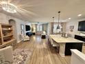Spacious open-concept living area with hardwood floors, modern lighting, a large island with bar seating, and comfortable furniture at 384 Summer Squall Rd, Davenport, FL 33837