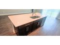 Kitchen island with a sink, white countertop, and dark cabinets at 1867 Holden Ridge Lane, Clermont, FL 34715