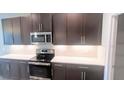 Contemporary kitchen features stainless steel appliances and dark cabinetry at 1867 Holden Ridge Lane, Clermont, FL 34715