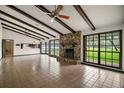 Bright living room featuring a stone fireplace, exposed beams, and large windows at 9335 Silver Lake Dr, Leesburg, FL 34788