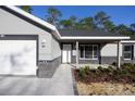 Close-up view of a home with light gray exterior, new walkway, and fresh landscaping by the front entryway at 1243 Ne 130Th Ter, Silver Springs, FL 34488