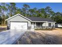 Well-maintained single-story home with a gray exterior, concrete driveway, attached garage, and manicured front yard at 1243 Ne 130Th Ter, Silver Springs, FL 34488