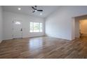 Bright living room with wood-look flooring, a ceiling fan, white walls, and a view of the front yard at 1243 Ne 130Th Ter, Silver Springs, FL 34488